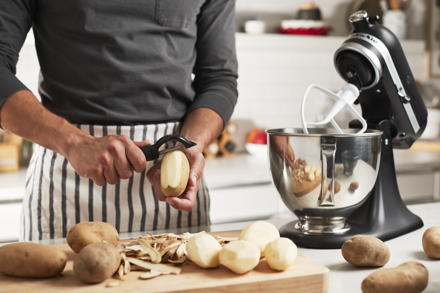 Person peeling potatoes next to a stand mixer