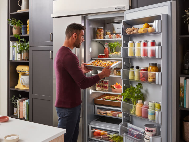 Man pulling sheet of fresh pasta from refrigerator