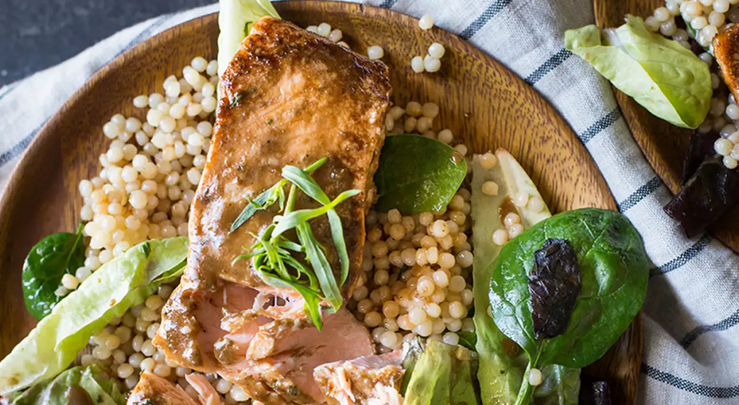 Salmon, couscous and greens on dinner plate