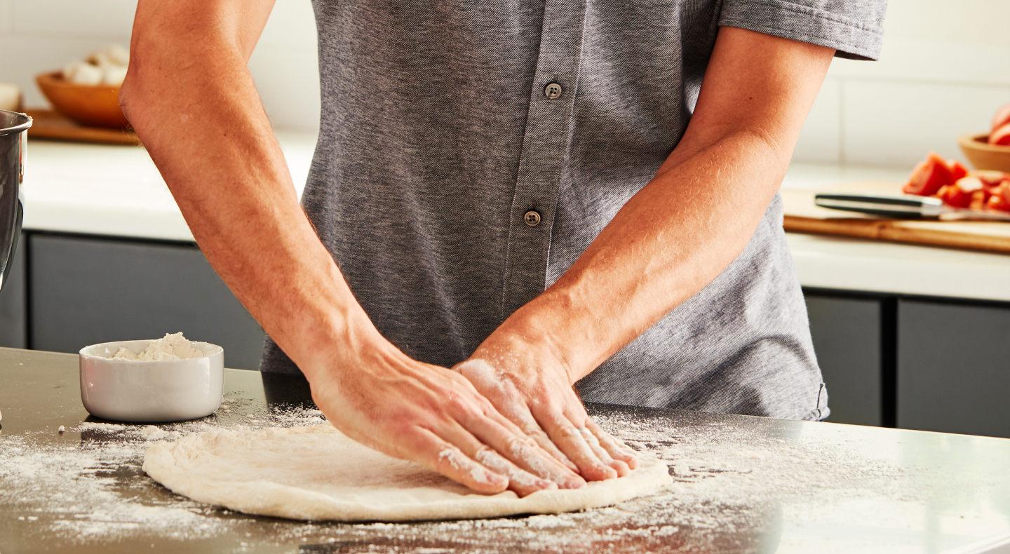 Person stretching out homemade pizza dough