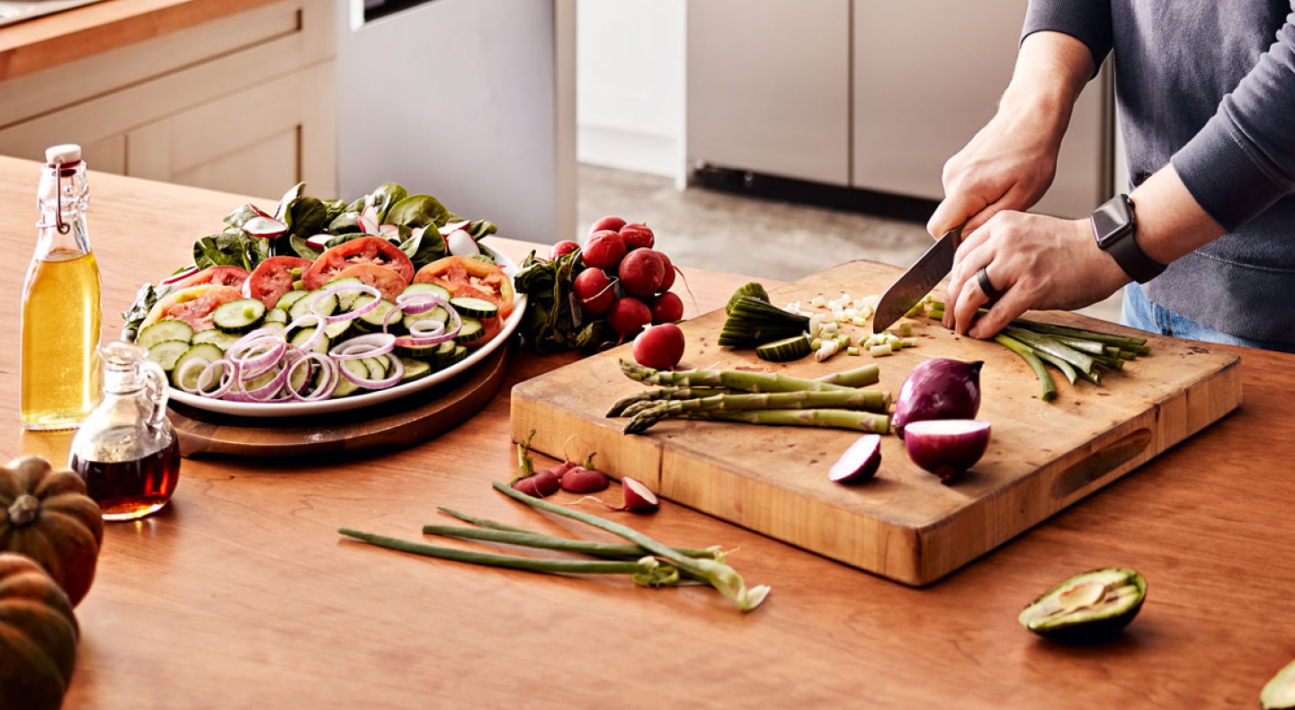Maker chopping vegetables on wooden cutting board