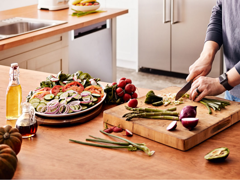 Maker chopping vegetables on wooden cutting board
