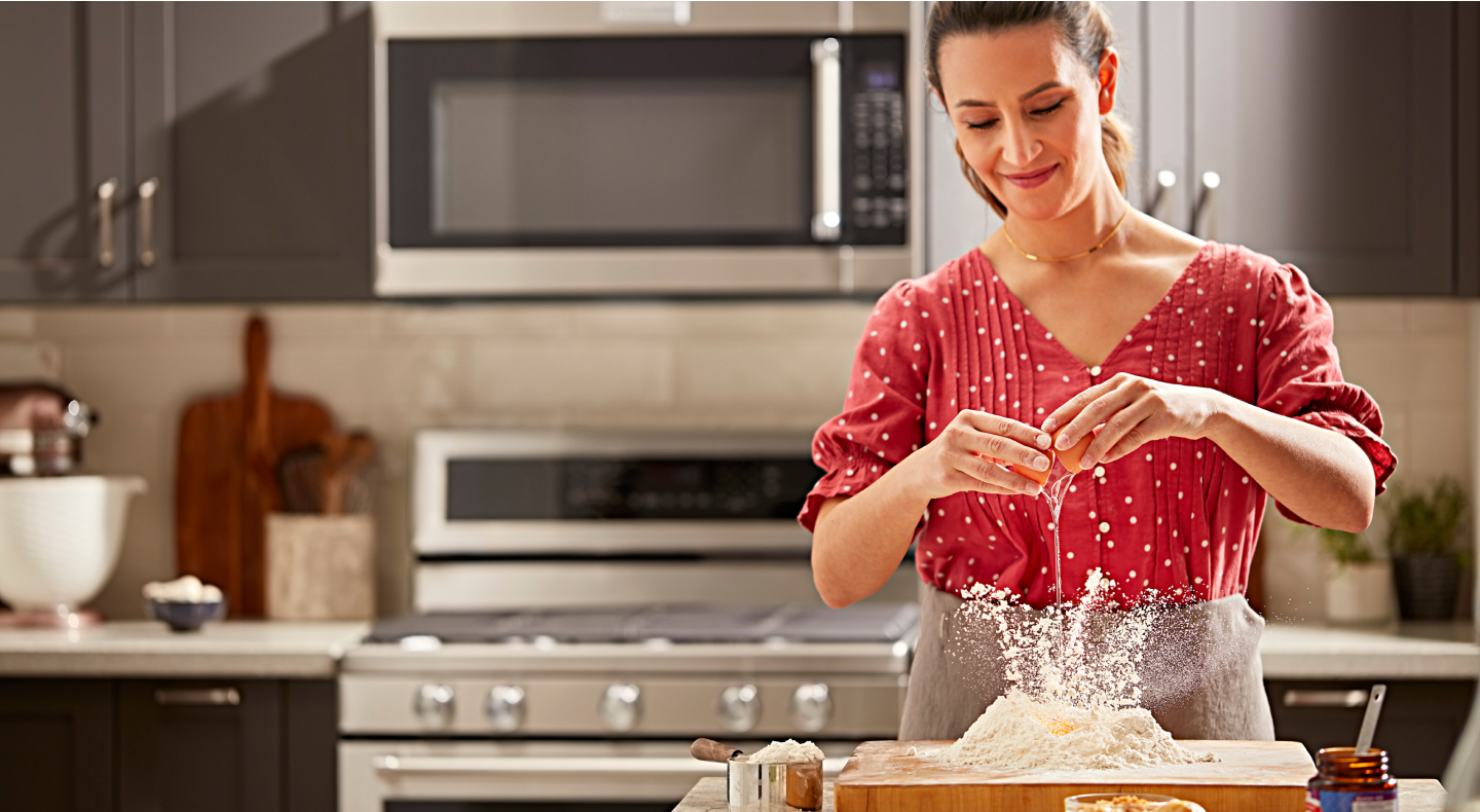 Woman adding eggs to flour mound 