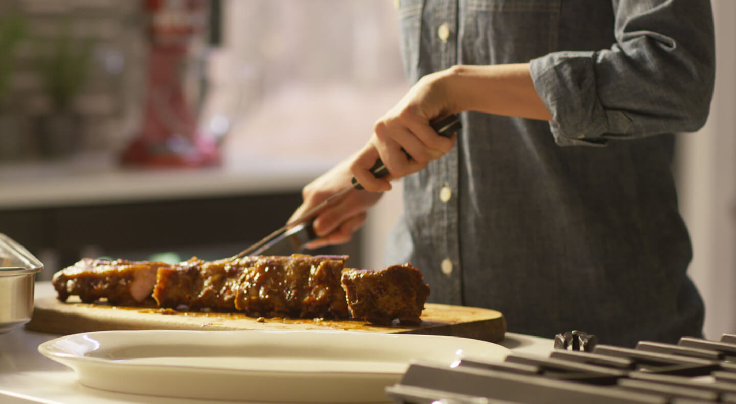 Cook cutting into a tender rack of ribs.