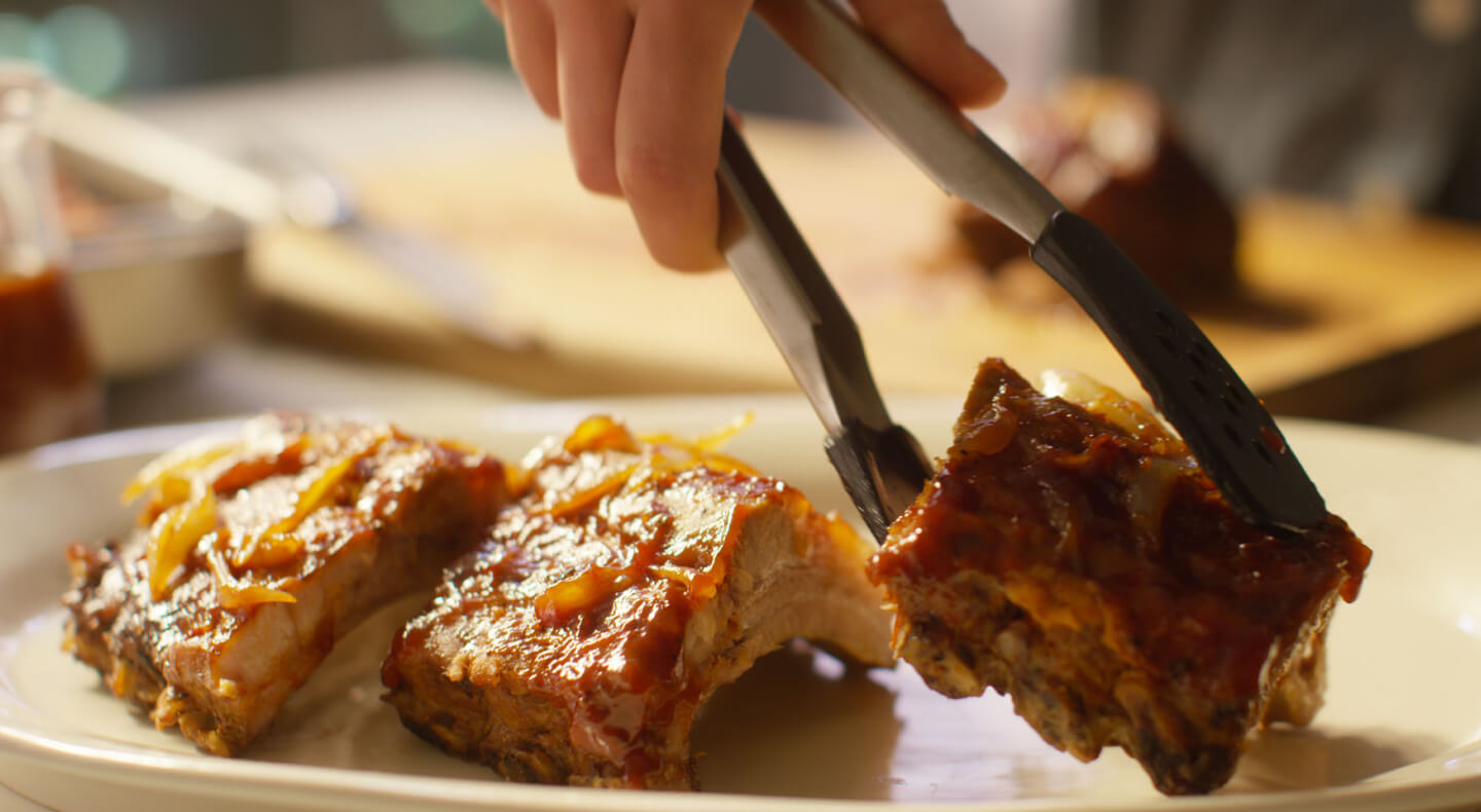 Three pieces of oven baked ribs with sauce.