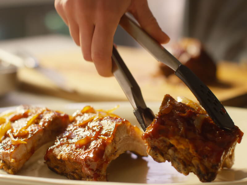 Three pieces of oven baked ribs with sauce.