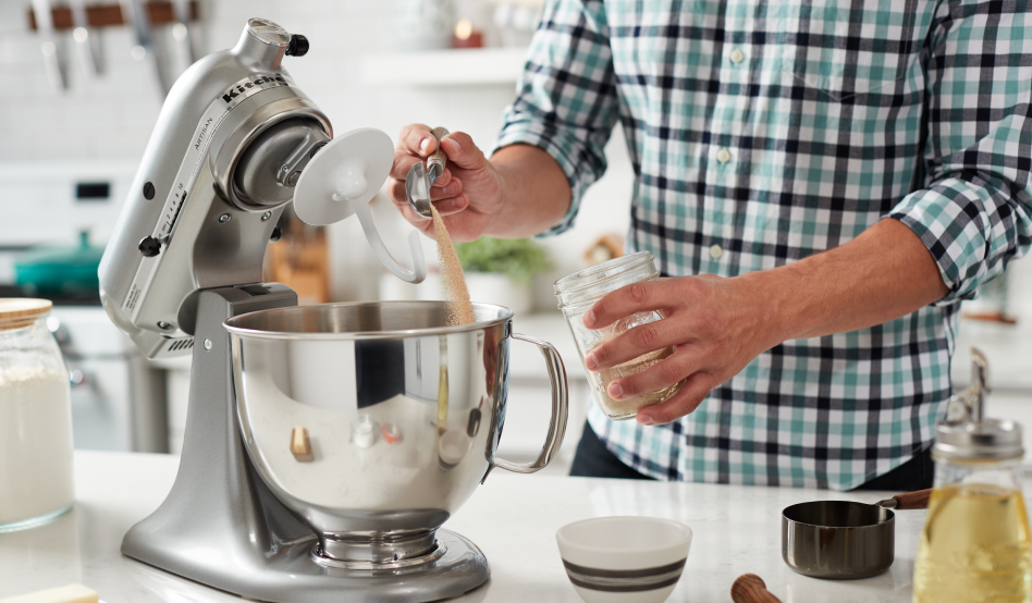 Person adding ingredients stand mixer for sandwich bread