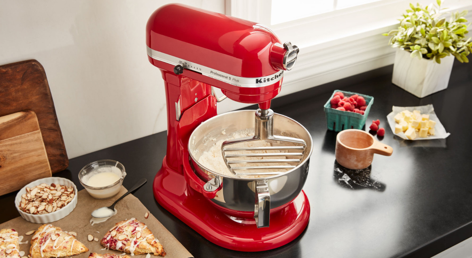 KitchenAid® pastry beater in bowl of  KitchenAid® stand mixer next to homemade scones