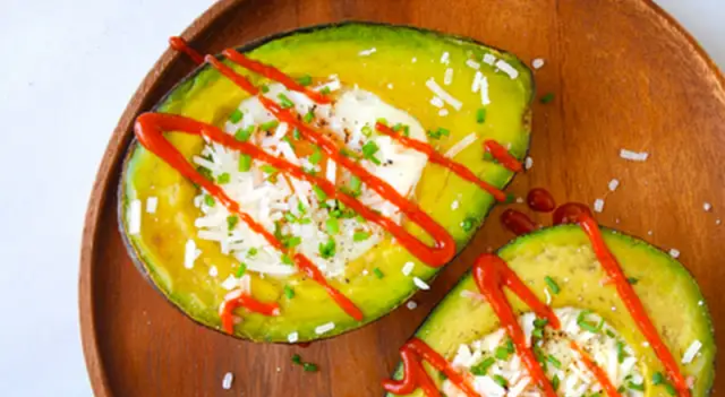 Baked avocado eggs with a drizzle of sriracha