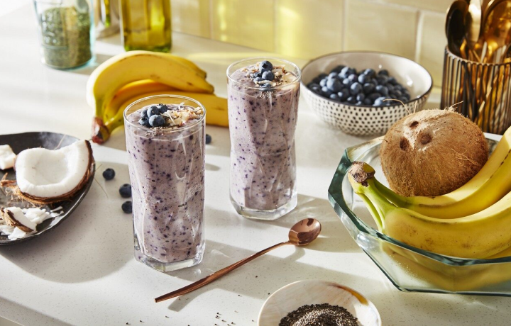 Two smoothies on a counter surrounded by ingredients