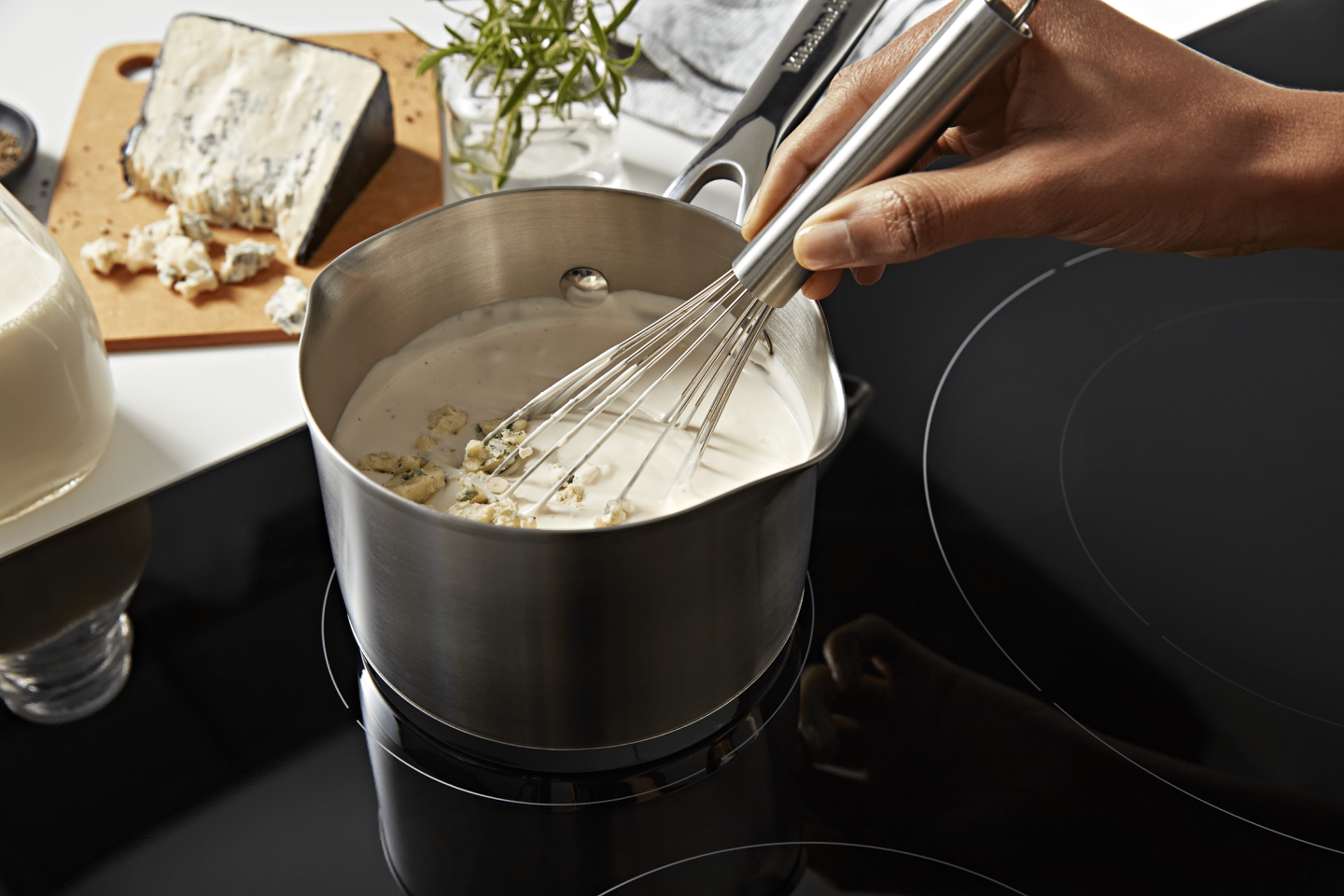 A person whisking a pot of vegan queso.