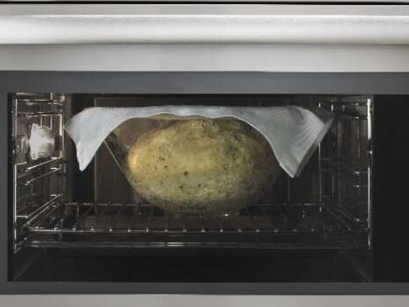Bread rising in a glass bowl, with a cloth on top, inside of a convection microwave