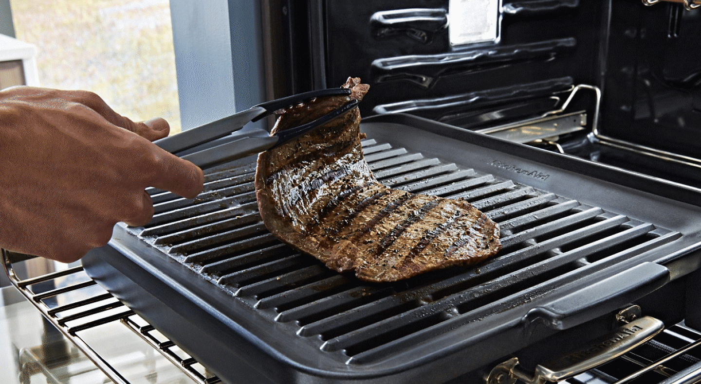 Hand lifting a cut of steak off of a rack