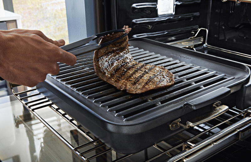 Hand lifting a cut of steak off of a rack