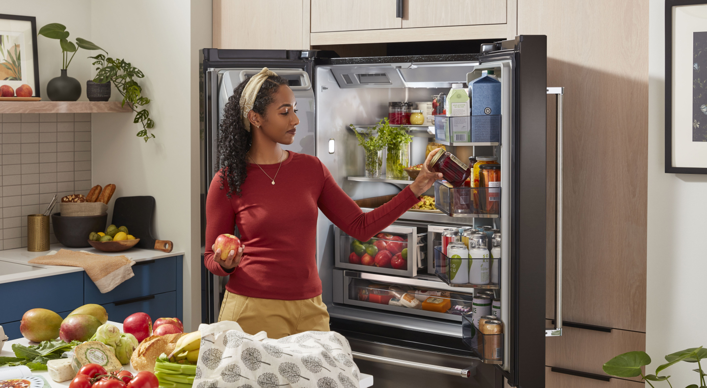 Person removing items from the door of a refrigerator