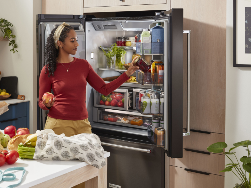 Person removing items from the door of a refrigerator