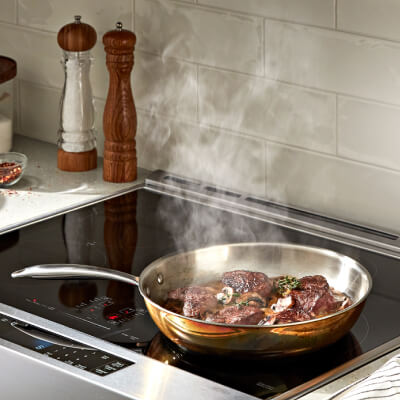 Steak cooking on a cooktop