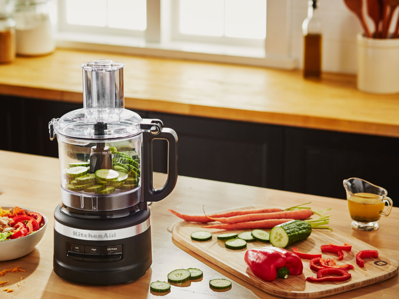 Sliced cucumbers inside a black KitchenAid® food processor