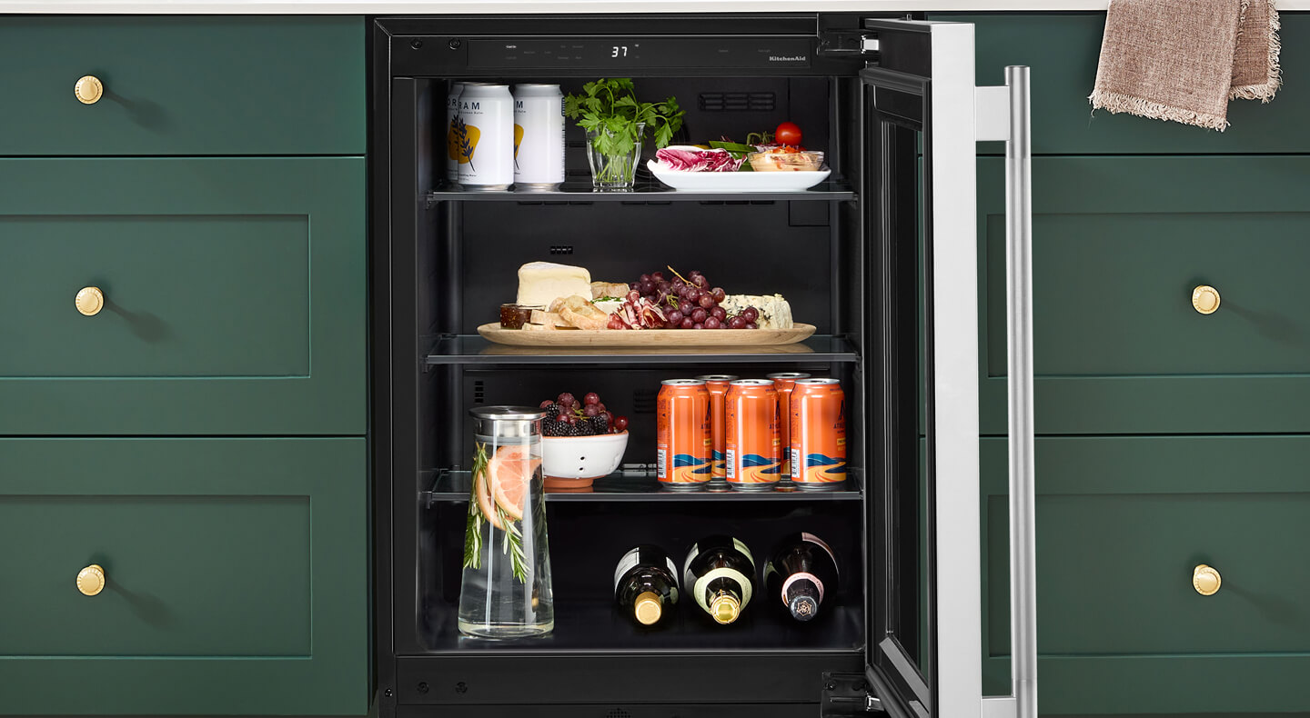 Open undercounter refrigerator with beverages and charcuterie inside