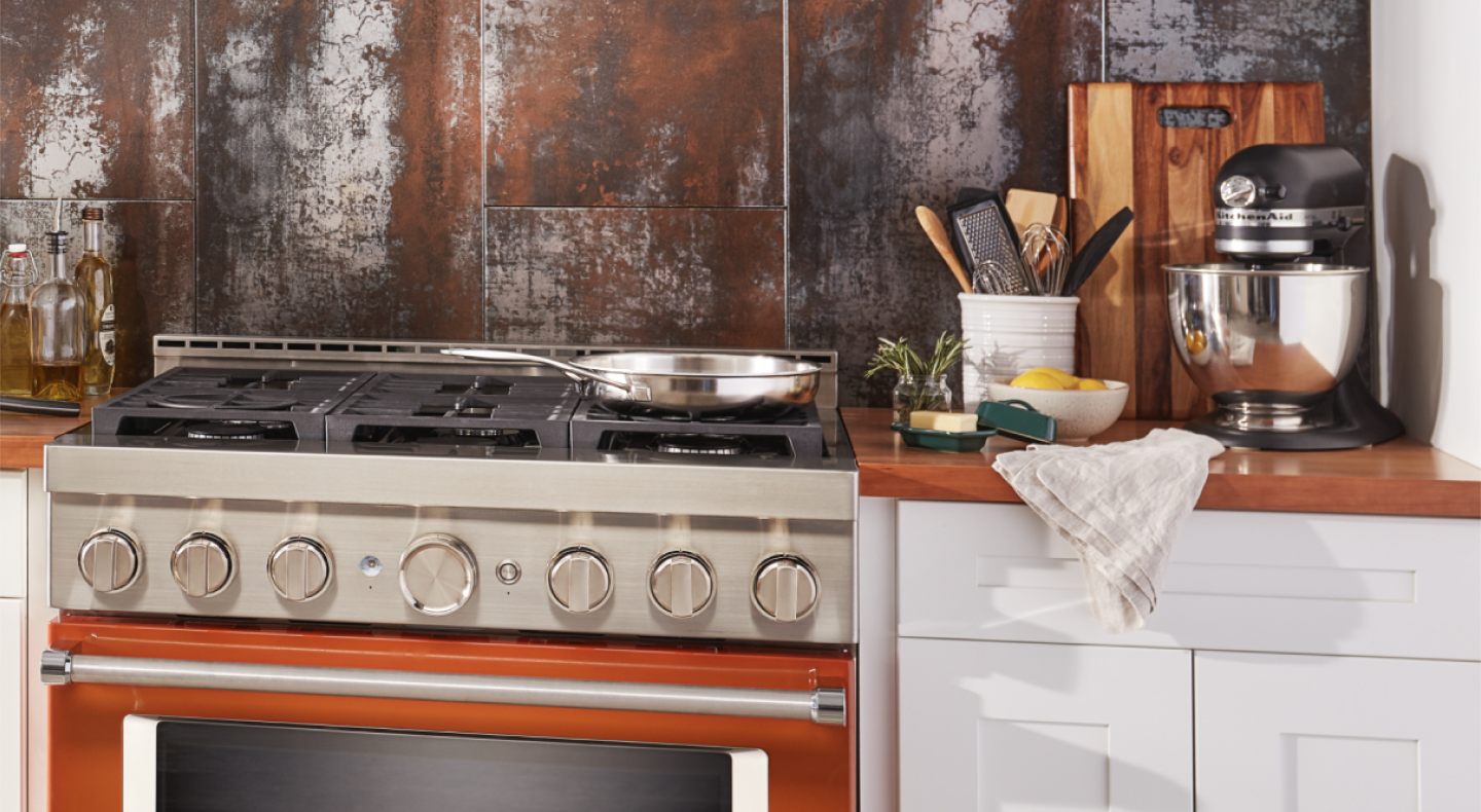 A black KitchenAid® stand mixer on the counter next to a gas range.