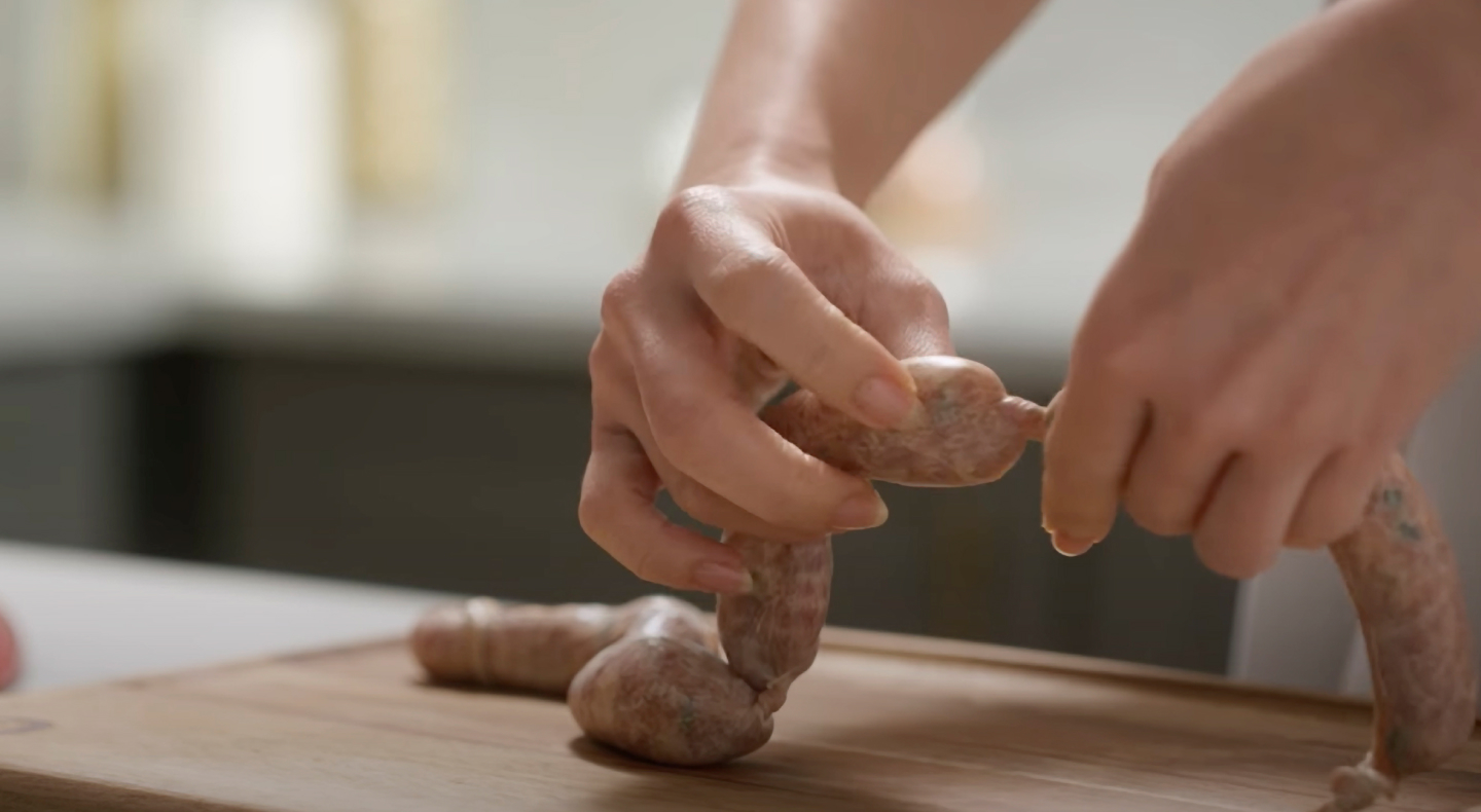 Person linking sausages