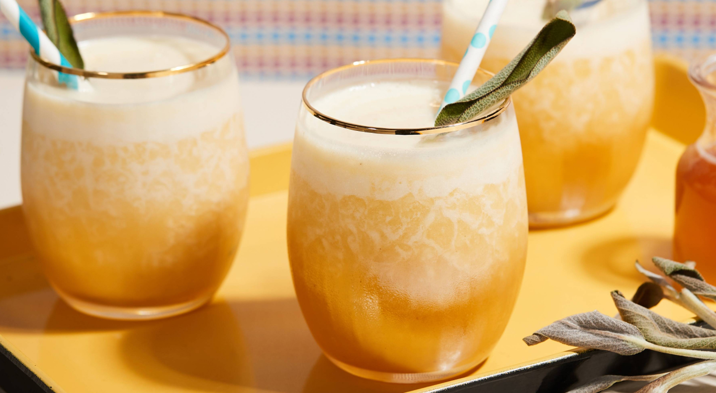 Fresh juice in serving cups with fruit pieces, straws and spoons