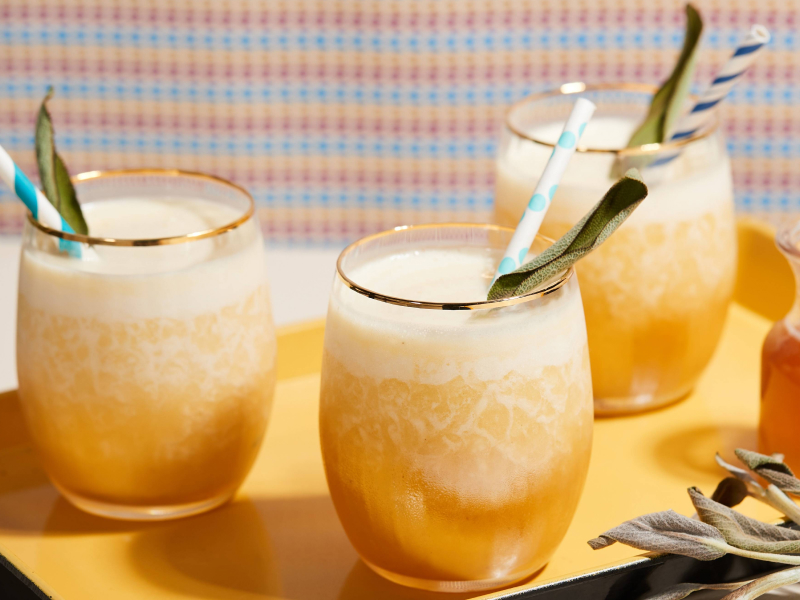 Fresh juice in serving cups with fruit pieces, straws and spoons