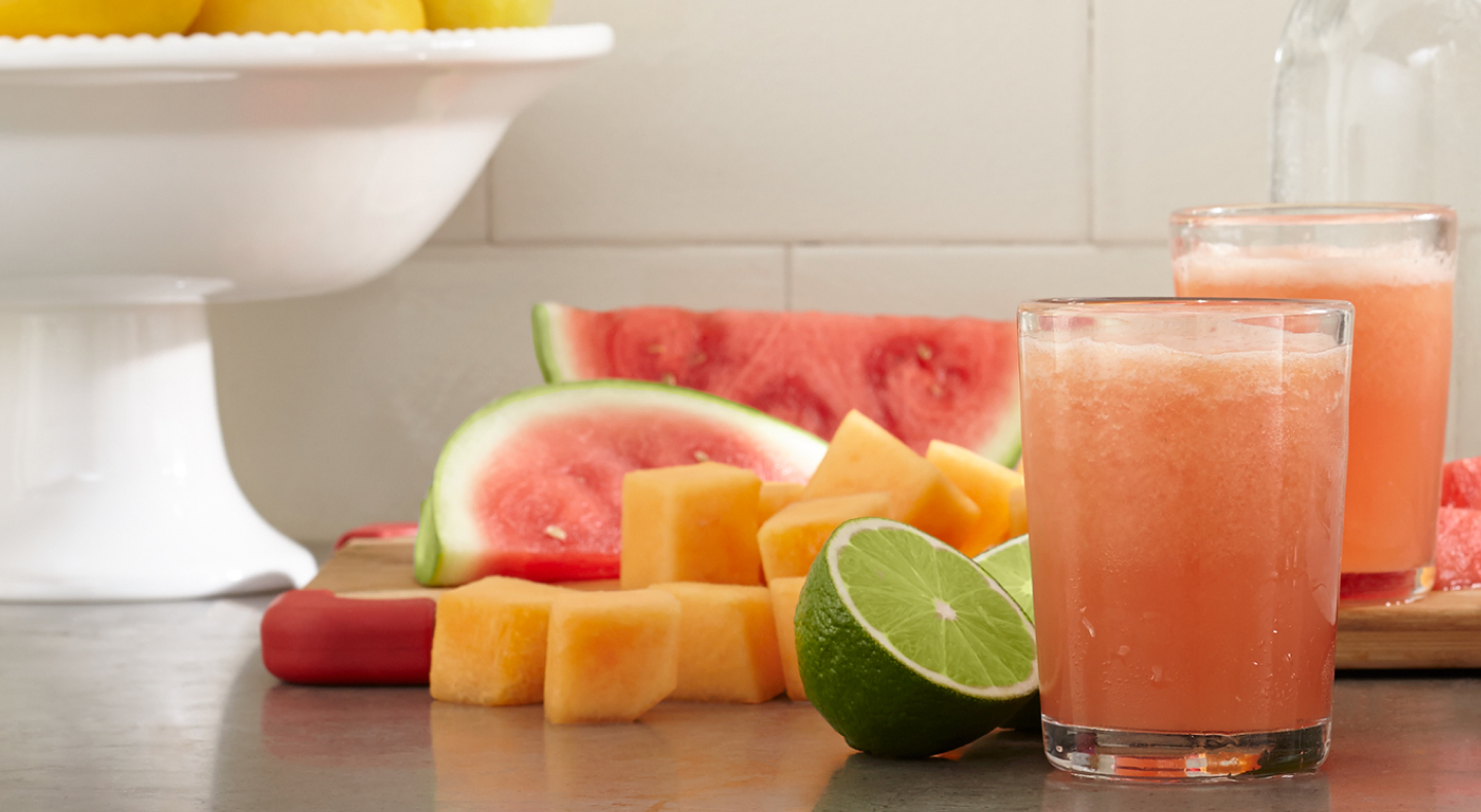 Glasses of fresh juice next to assorted fruit pieces