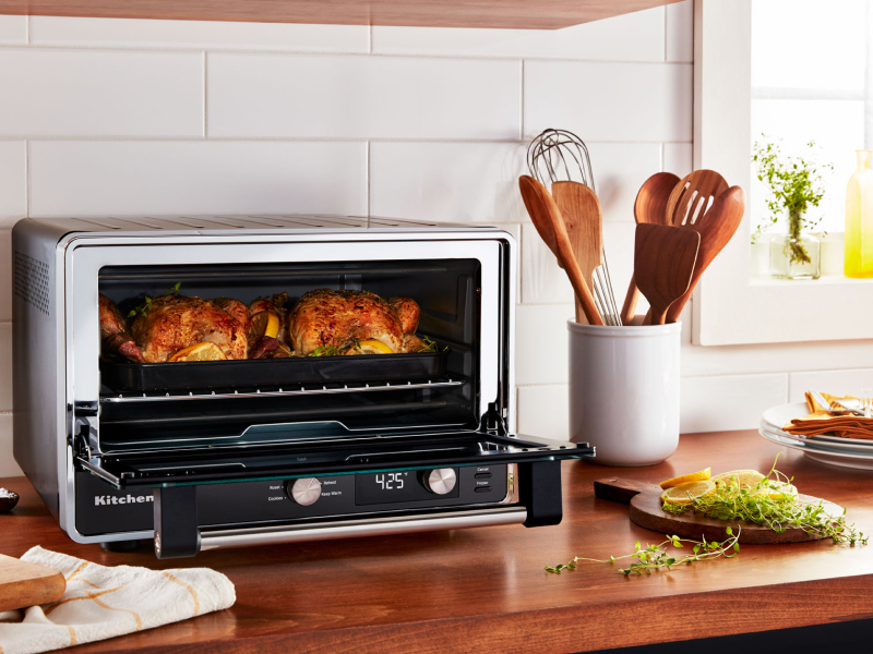 Two whole roasted chickens and greens cooked inside a KitchenAid® countertop oven