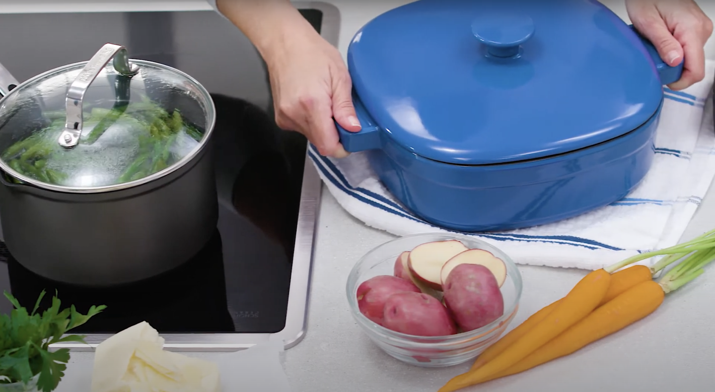 Person holding handles of dutch oven