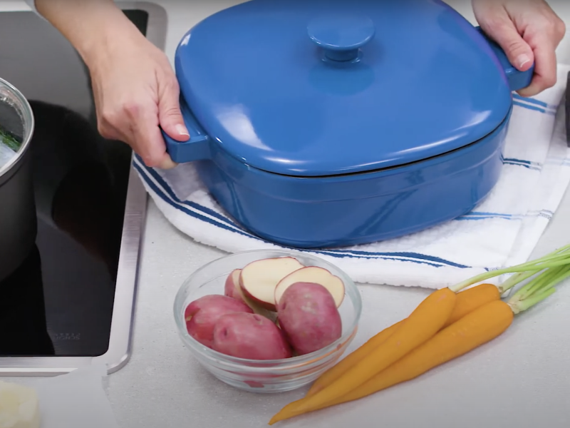 Person holding handles of dutch oven