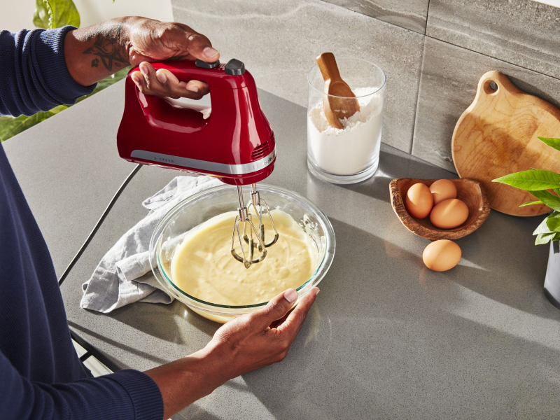 Person using KitchenAid® hand mixer over bowl of batter