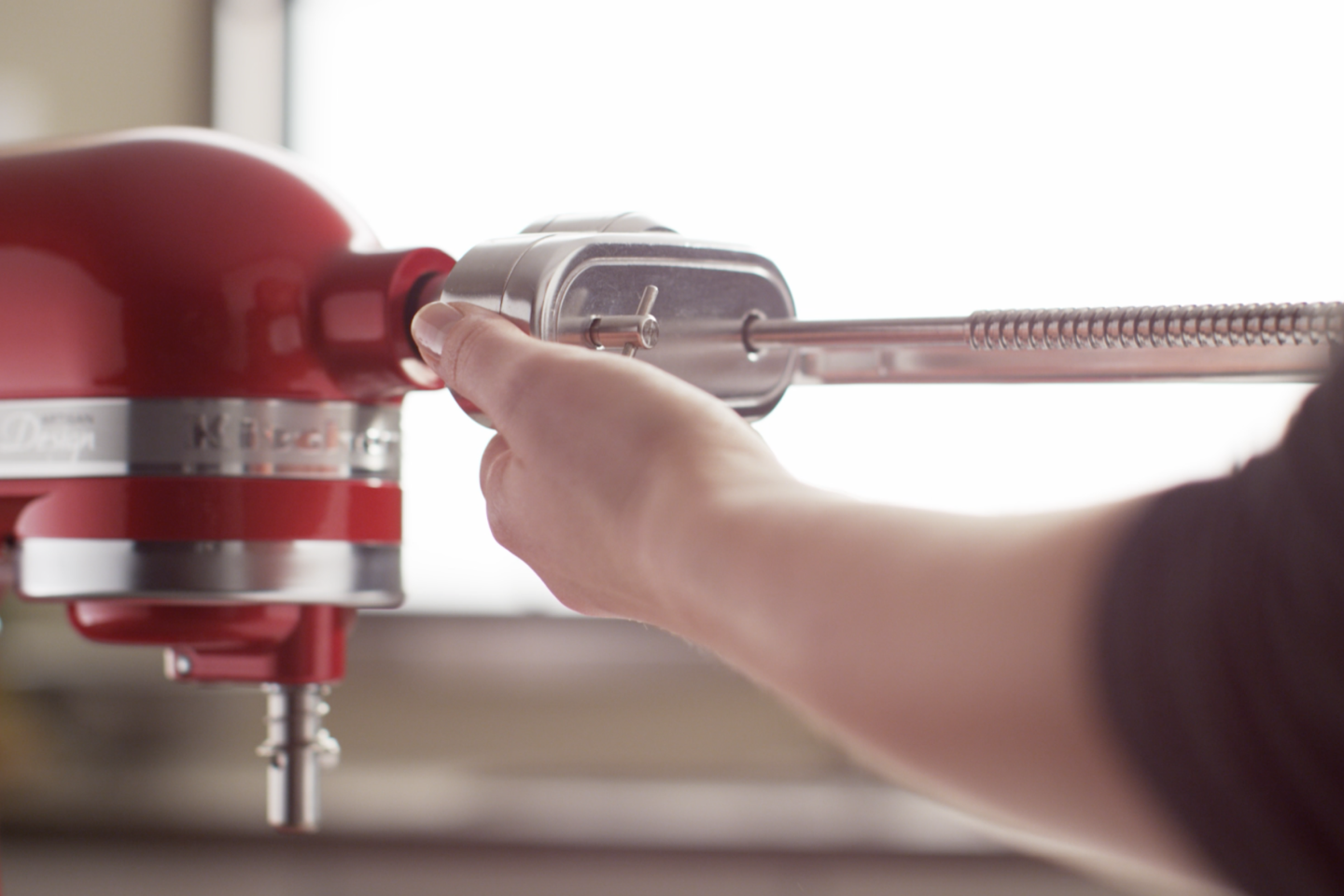 A person inserting an attachment into a stand mixer.
