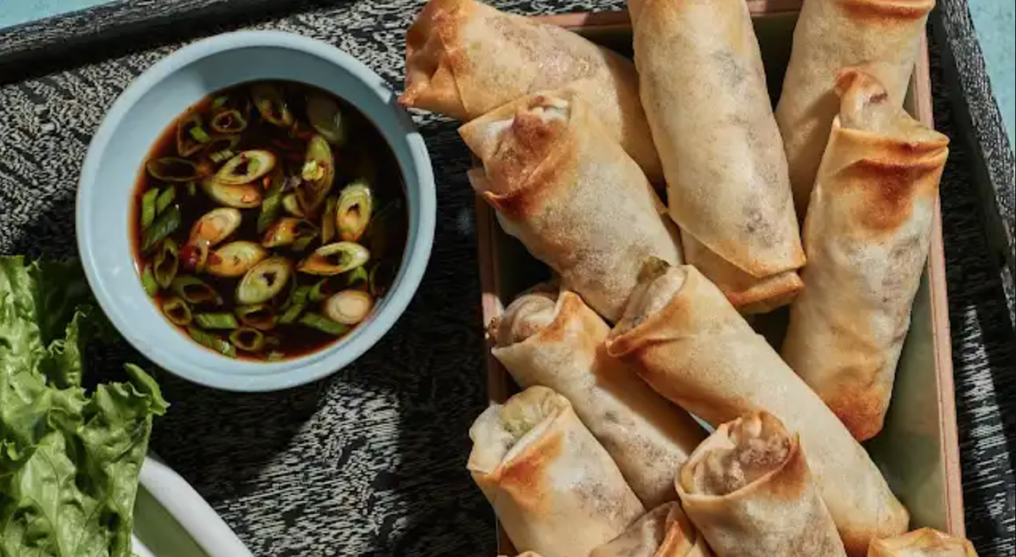 Egg rolls on dish next to dip. 
