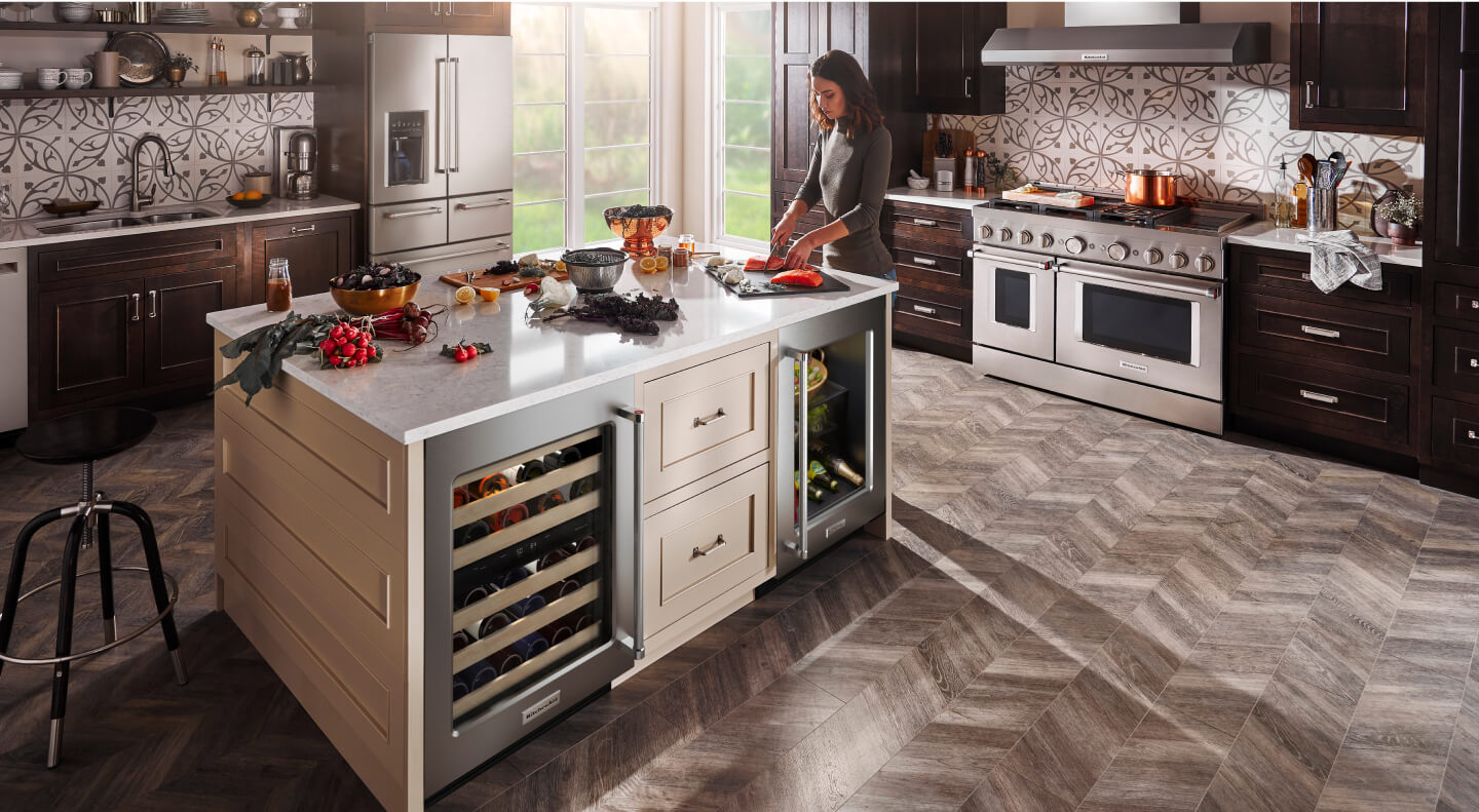 Woman cooking in a kitchen with stainless steel KitchenAid® appliances