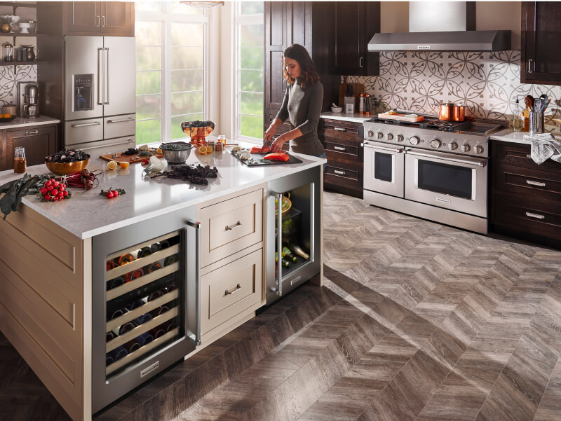 Woman cooking in a kitchen with stainless steel KitchenAid® appliances