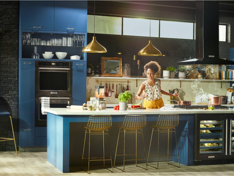 Woman cooking in a kitchen with black stainless steel KitchenAid® appliances