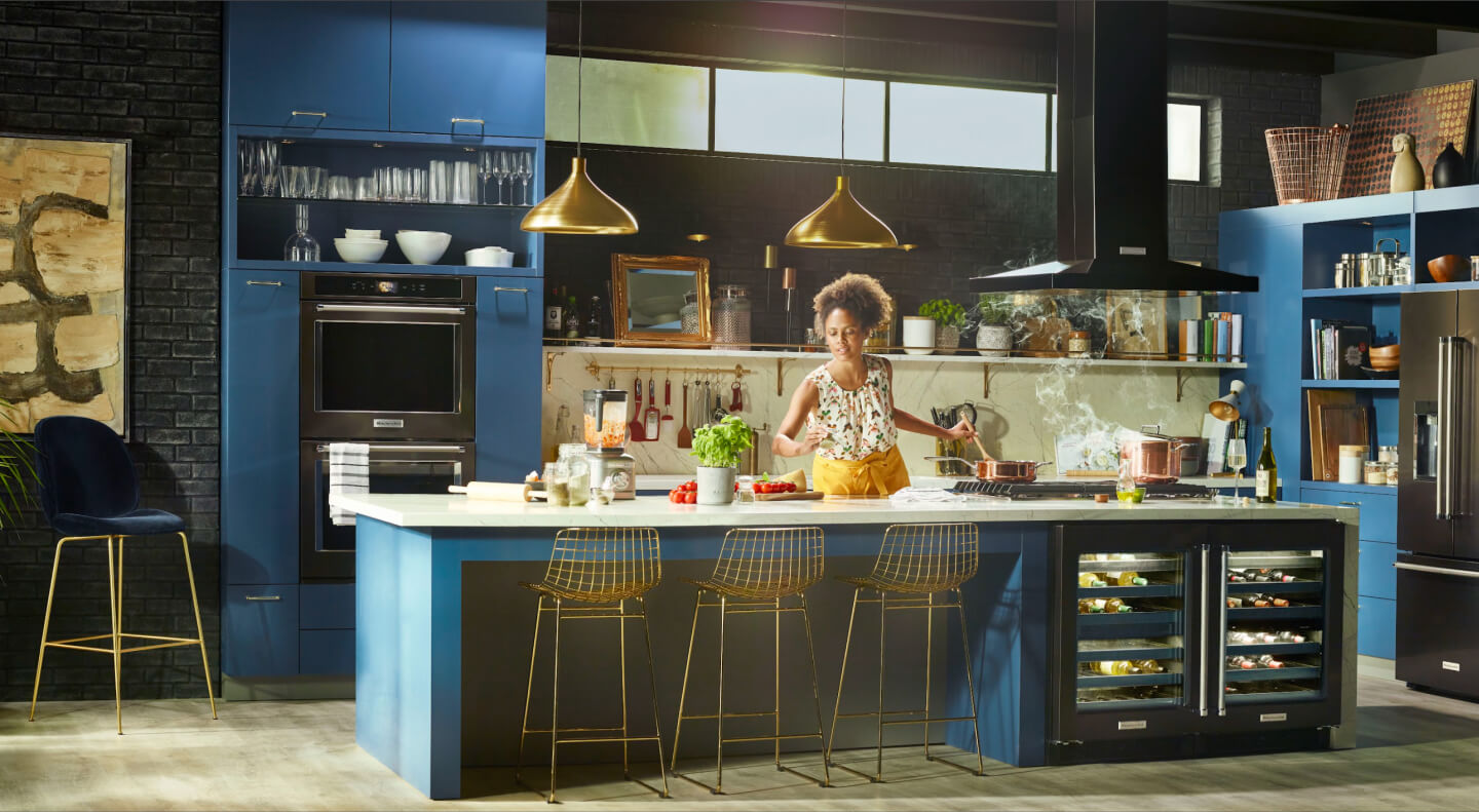Woman cooking in a kitchen with black stainless steel KitchenAid® appliances