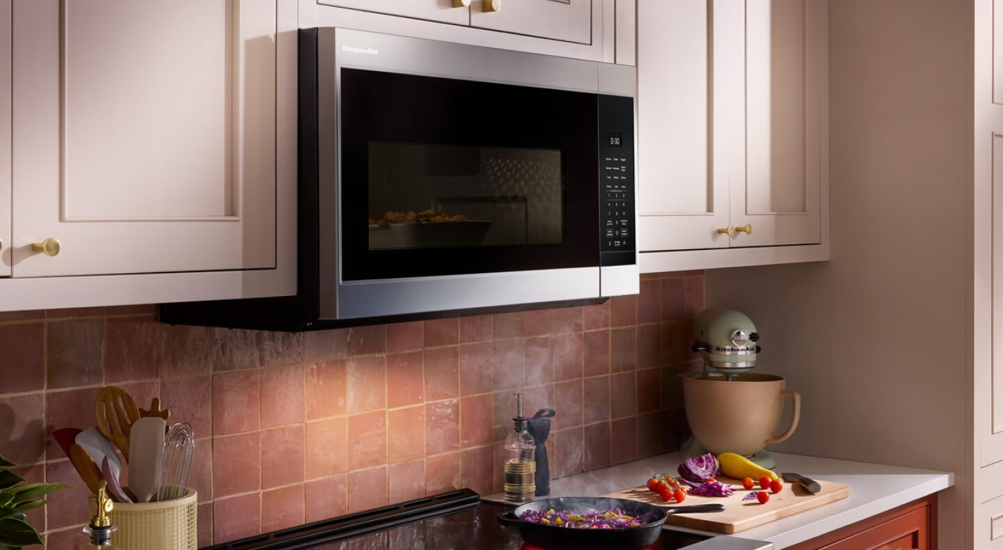 KitchenAid® over-the-range microwave above brick-colored backsplash