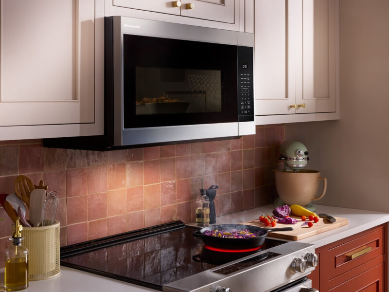 KitchenAid® over-the-range microwave above brick-colored backsplash