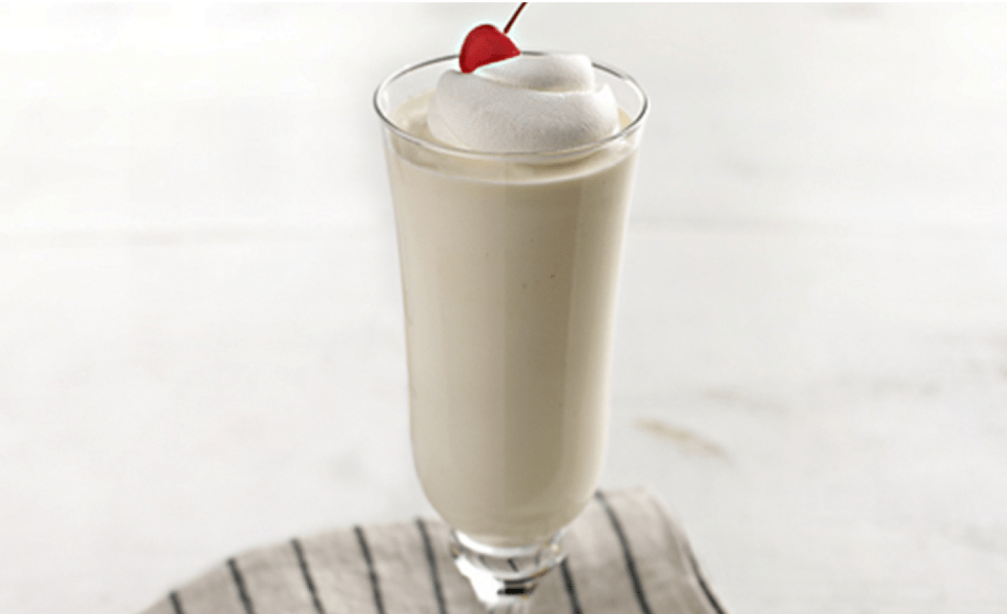 Vanilla milkshake with whipped cream and a cherry on top