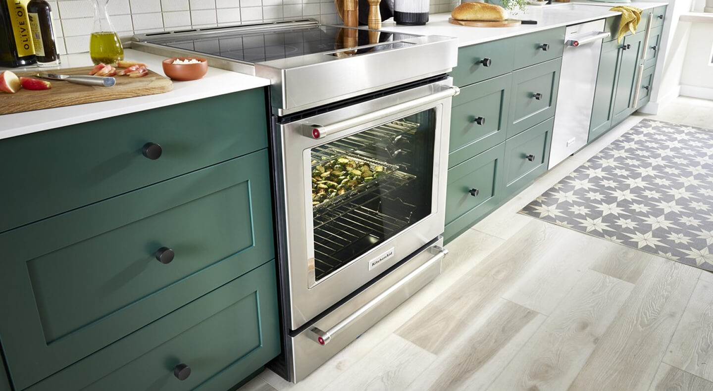 Stainless steel range set in green cabinetry