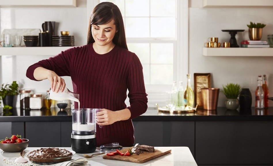 Smiling person pouring cream into a cordless food chopper