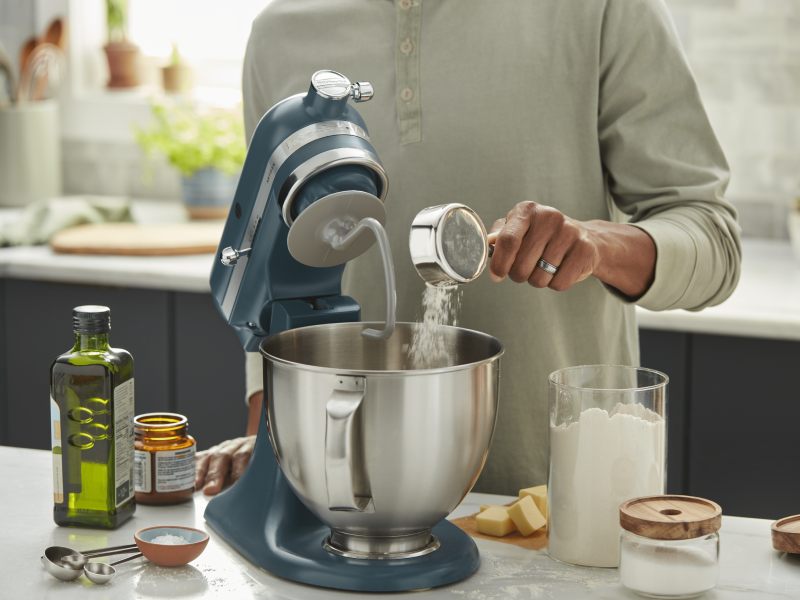 Person adding ingredients into a KitchenAid® stand mixer
