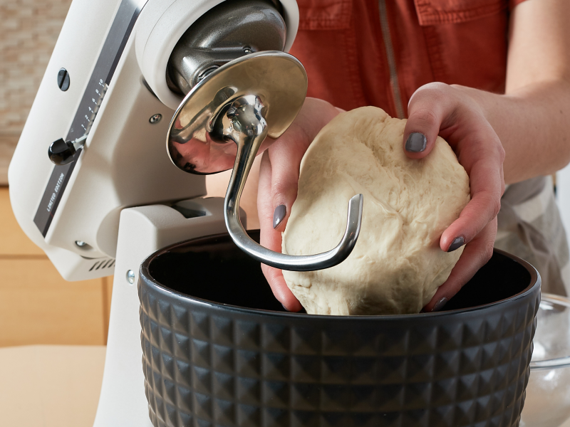Woman removing a ball of dough from a KitchenAid® stand mixer