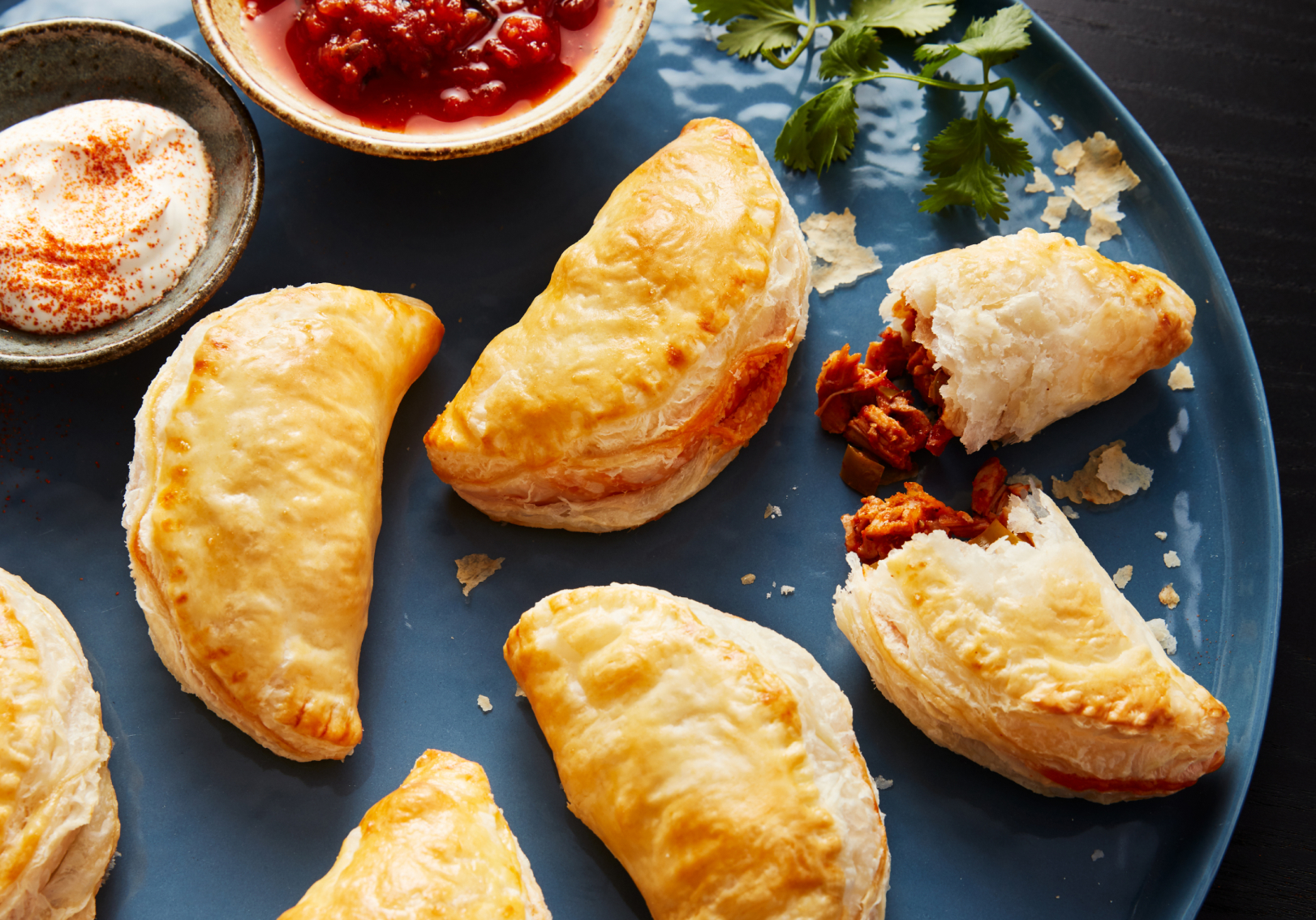  Empanadas on blue serving tray with dip