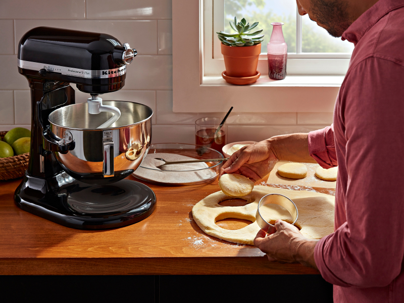 Person using a biscuit cutter to cut biscuit shapes into bread dough
