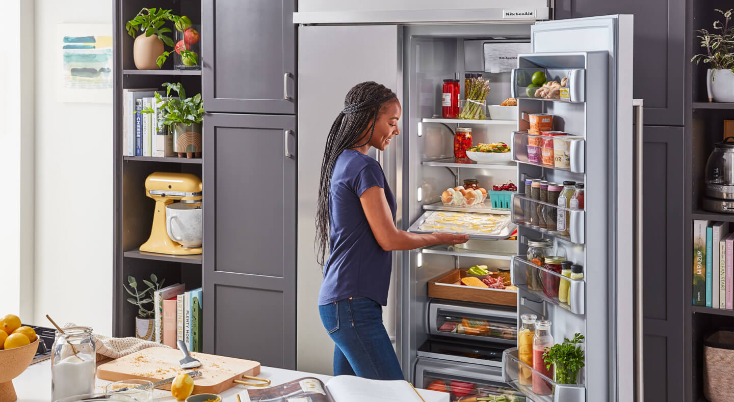Person retrieving a tray of food from a large capacity refrigerator