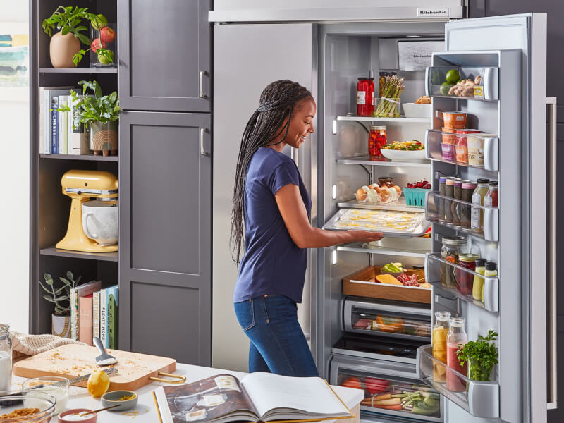 Person retrieving a tray of food from a large capacity refrigerator