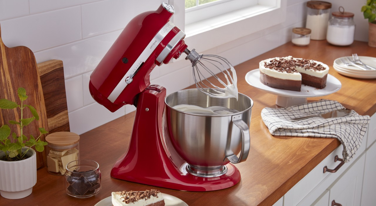 Red KitchenAid® stand mixer whipping cream next to pie on counter